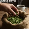 Close-up of a vibrant green Lintong coffee beans from a burlap sack, with a steaming cup of coffee in the background.