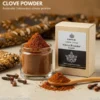 Premium Indonesian clove powder in a clear container next to export packaging labeled "Sherwah Clove Powder Export", with batik fabric and spices in the background.