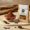 High-quality Indonesian clove powder in a glass jar, surrounded by culinary props, on a rustic surface.